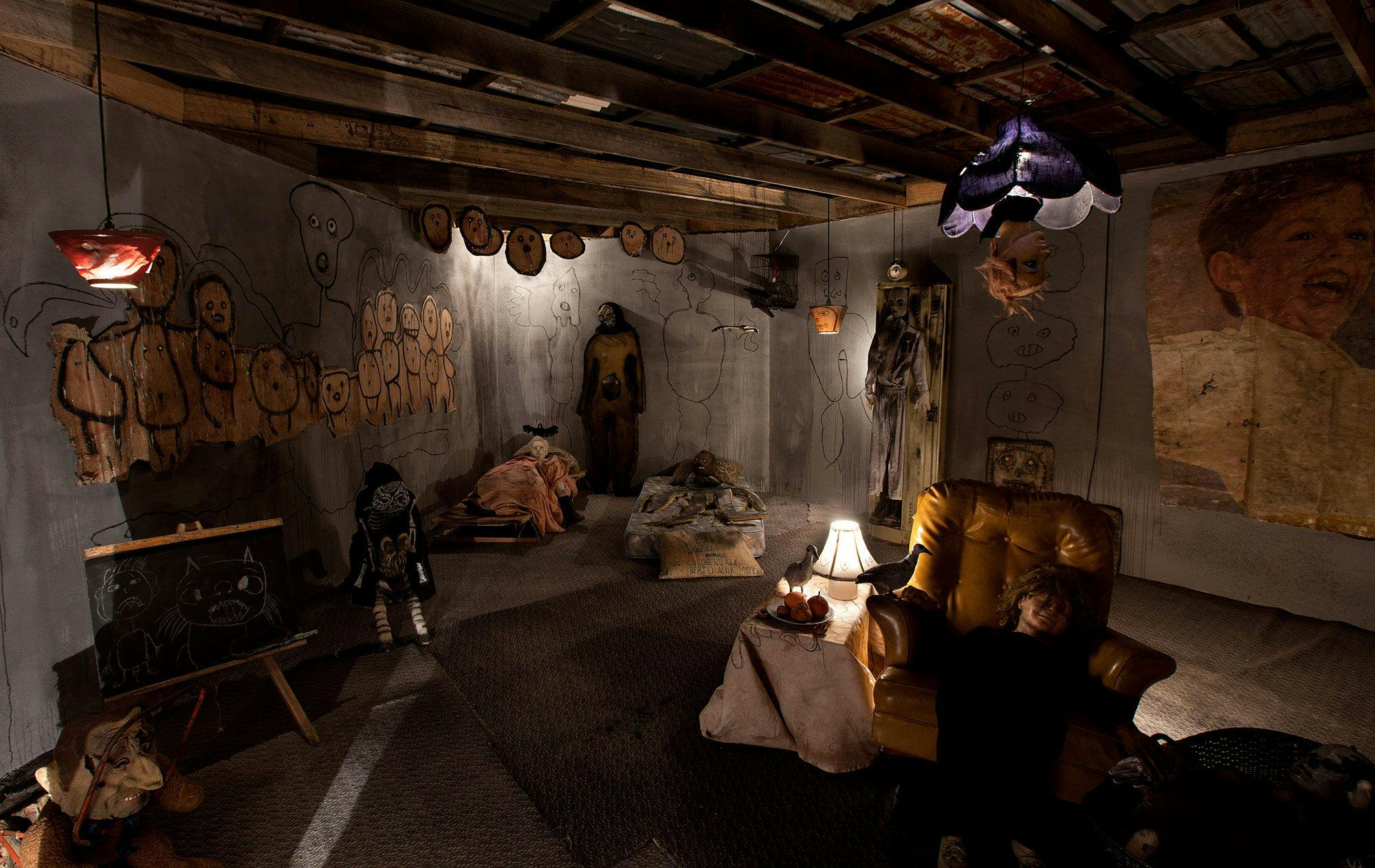 A dark grimy room filled with sculptures and drawings.