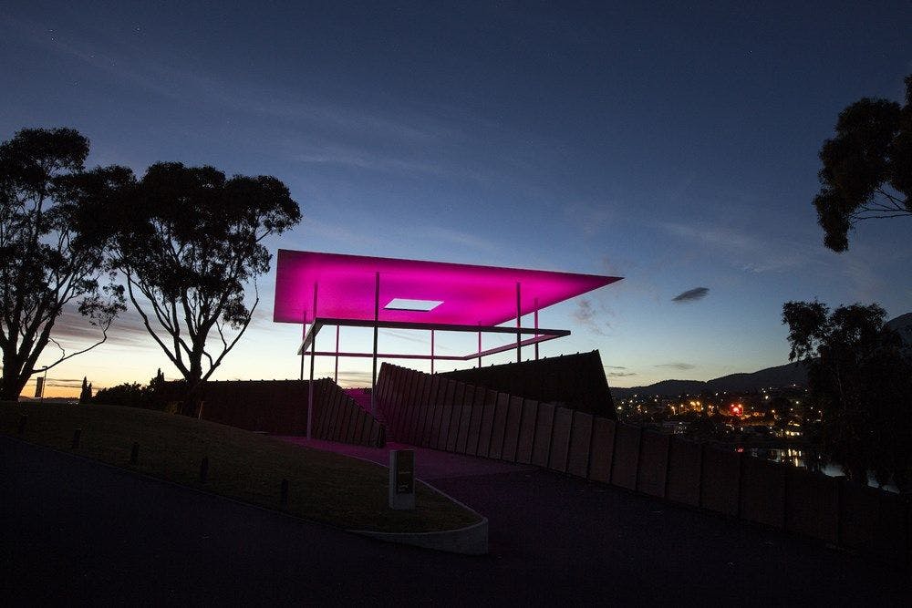 Sunsets behind a large structure with a pink glowing ceiling.