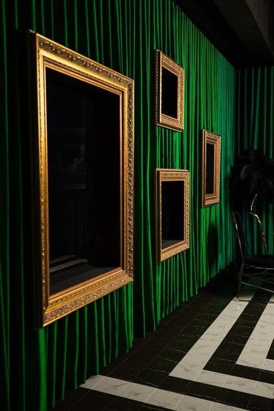 Gold framed mirrors on green floor to ceiling velvet curtains