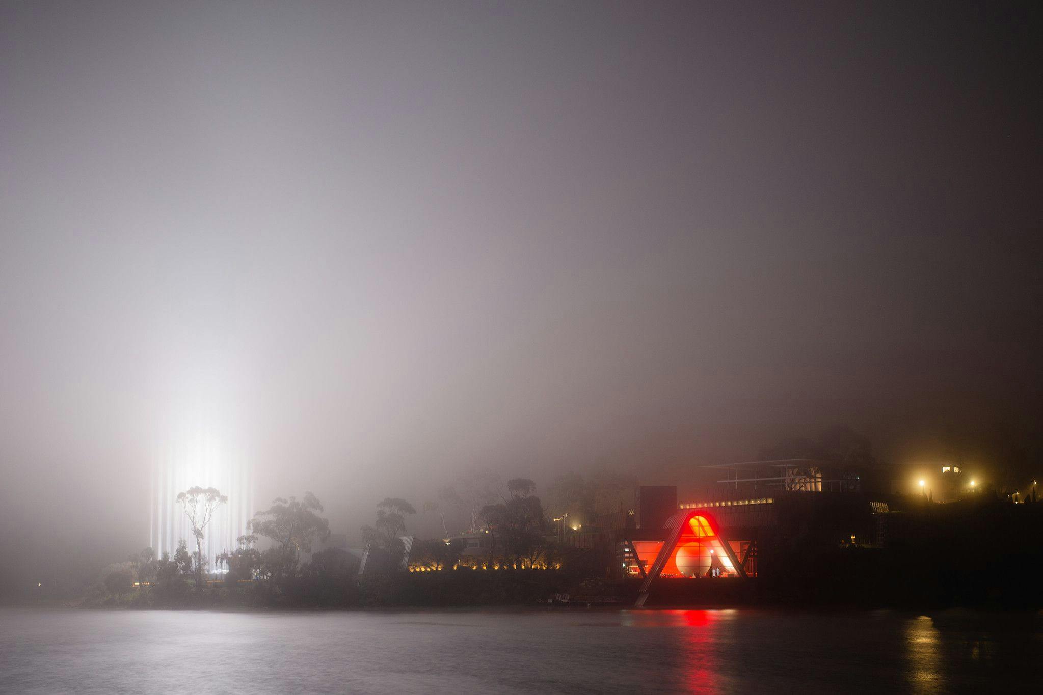 The Mona site lit red on a misty evening