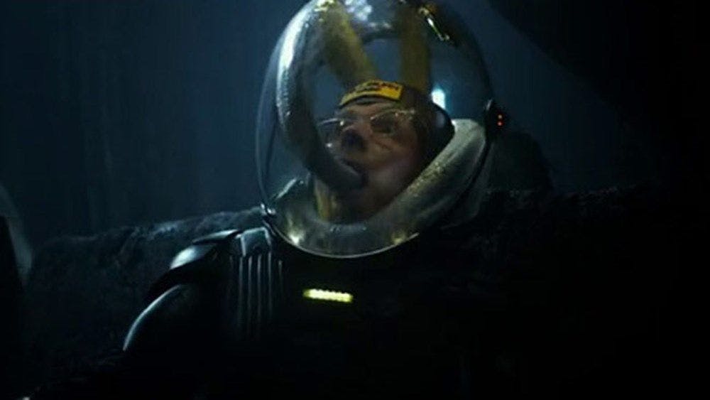 Person in domed space suit with snake like creature inside the helment entering their mouth.