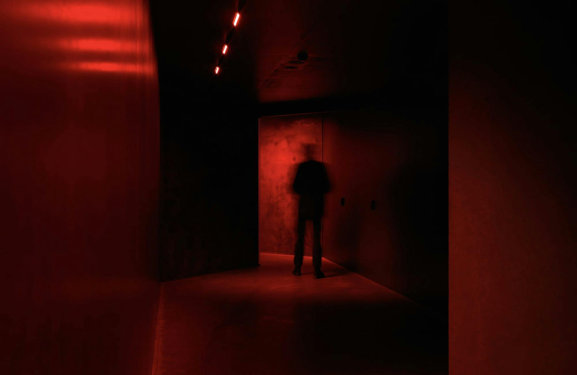A dark silhouette in a red lit hallway