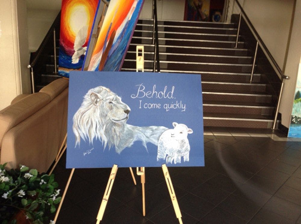 A painting of a lion and sheep on an easel, with the words "Behold, I come quickly."