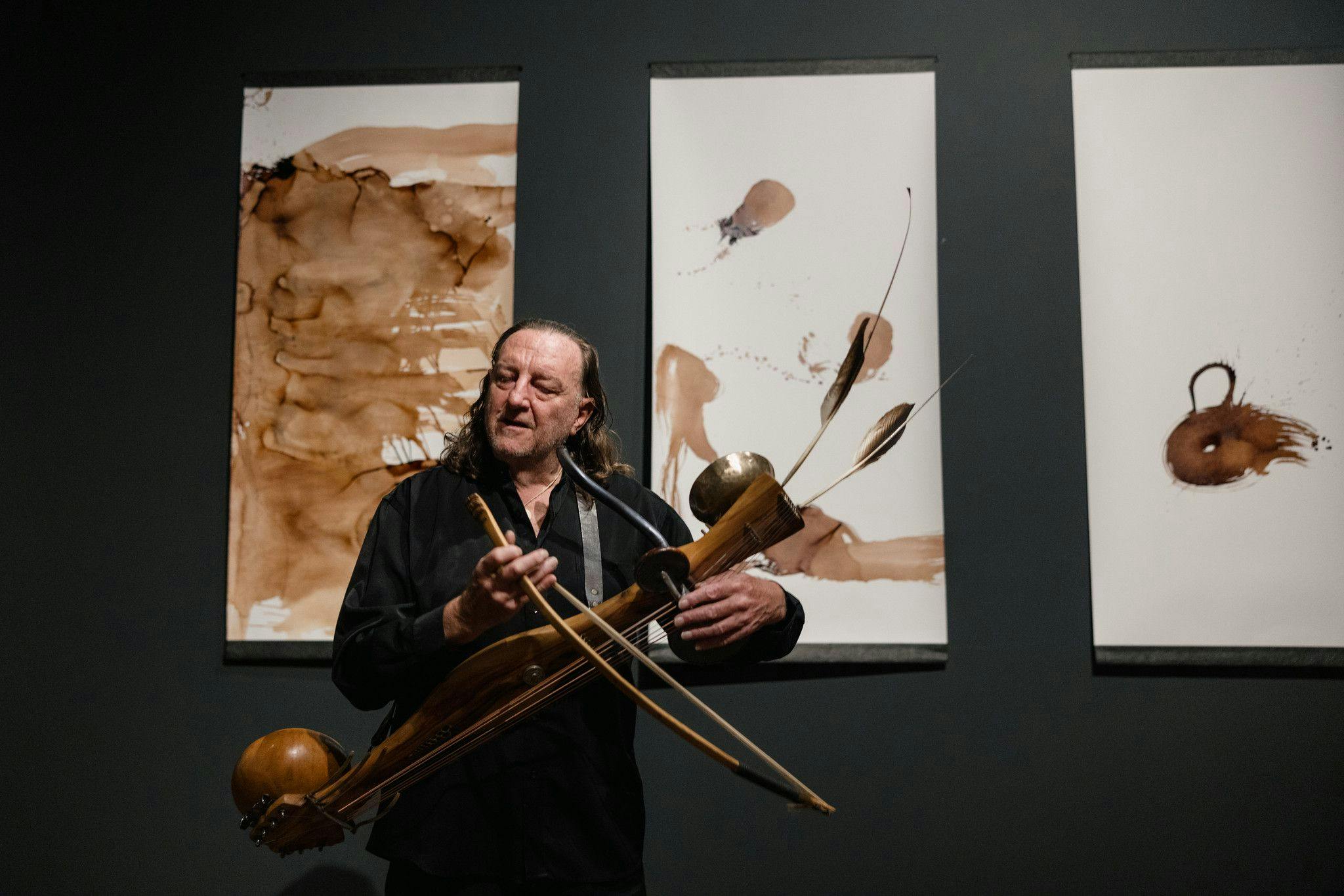 Colin Offord in the gallery playing one of his self made instruments of strings wood, feathers and a bow.