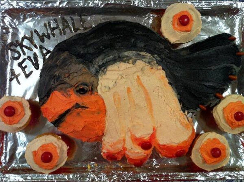 A birthday cake shaped like Skywhale with "SKYWHALE 4 EVA" written in icing