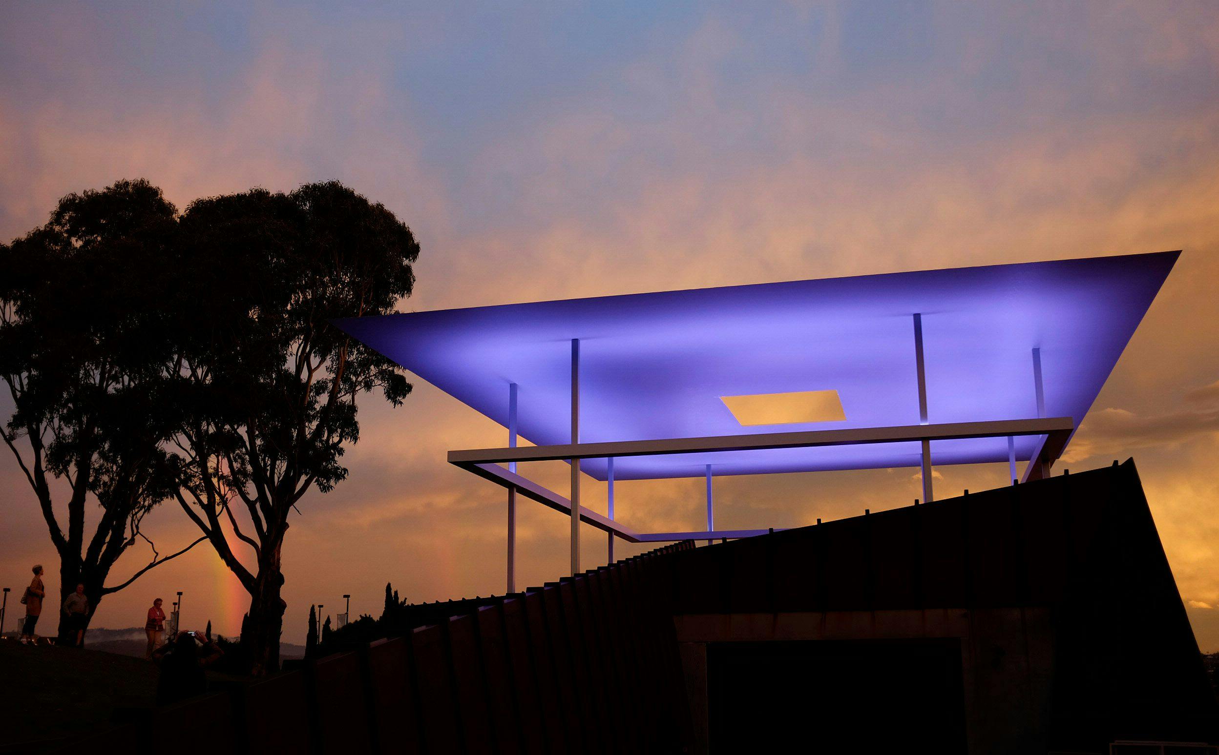 A large outdoor light installation, projecting blue/purple hues at night