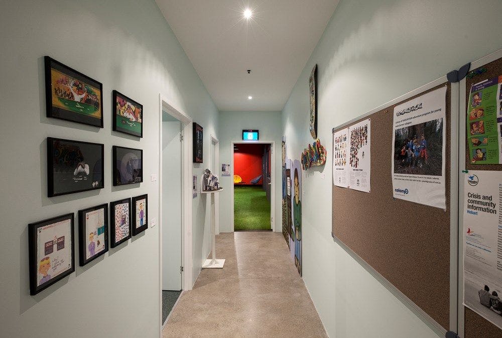A white hallway containing a message board and framed images