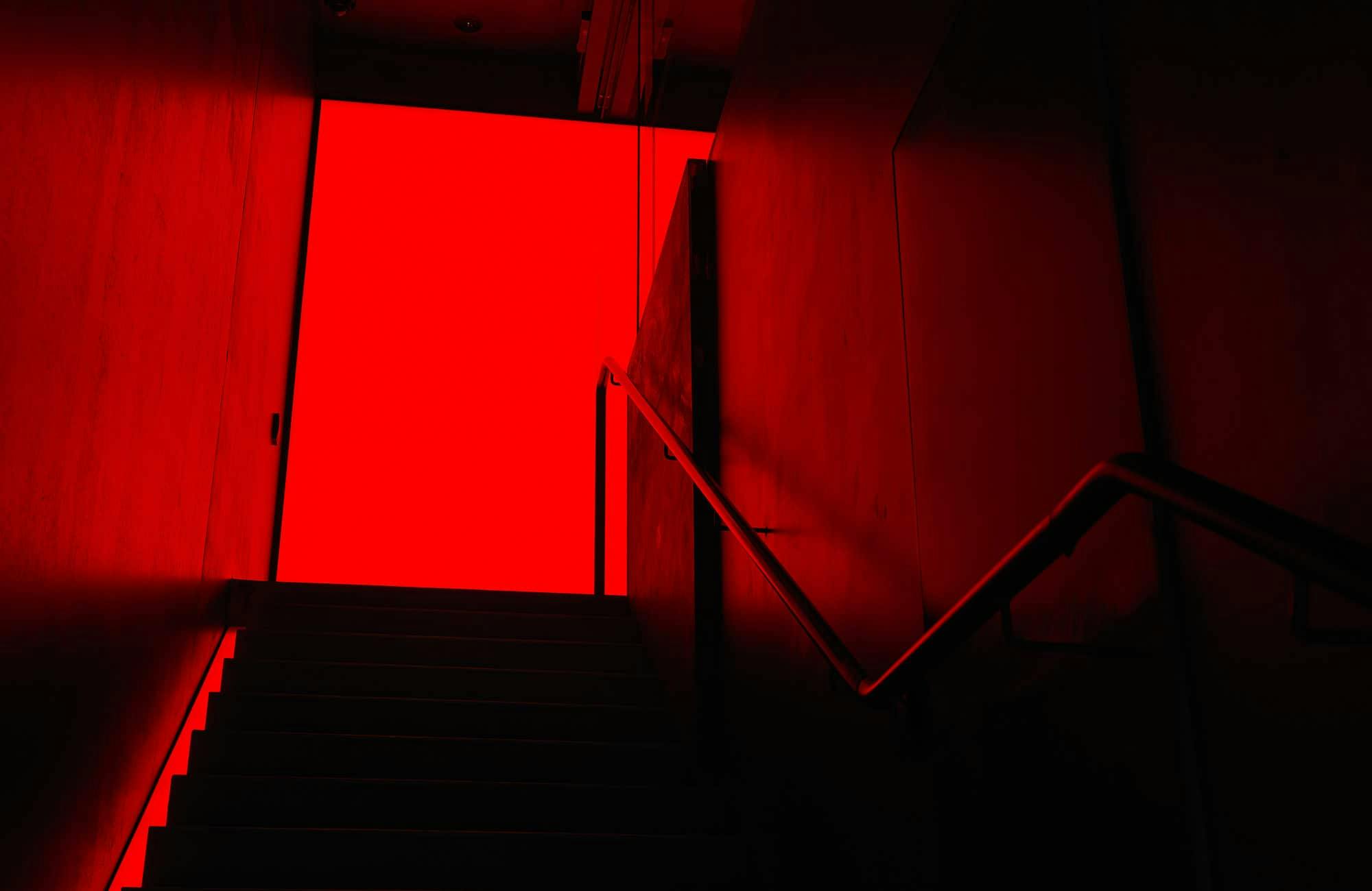 Dark staircase leading to a red door