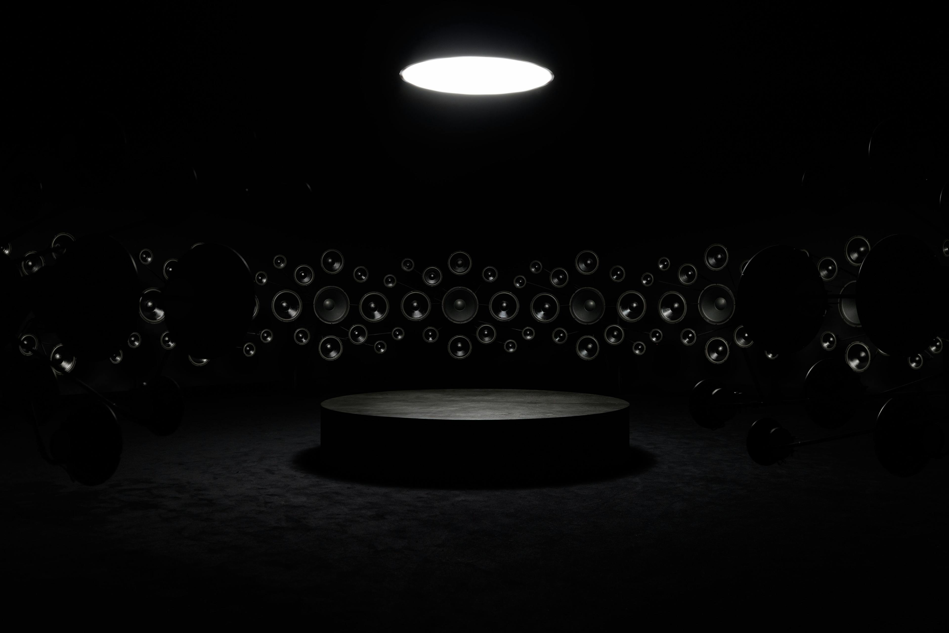 A dark circular room with speakers lining the walls.