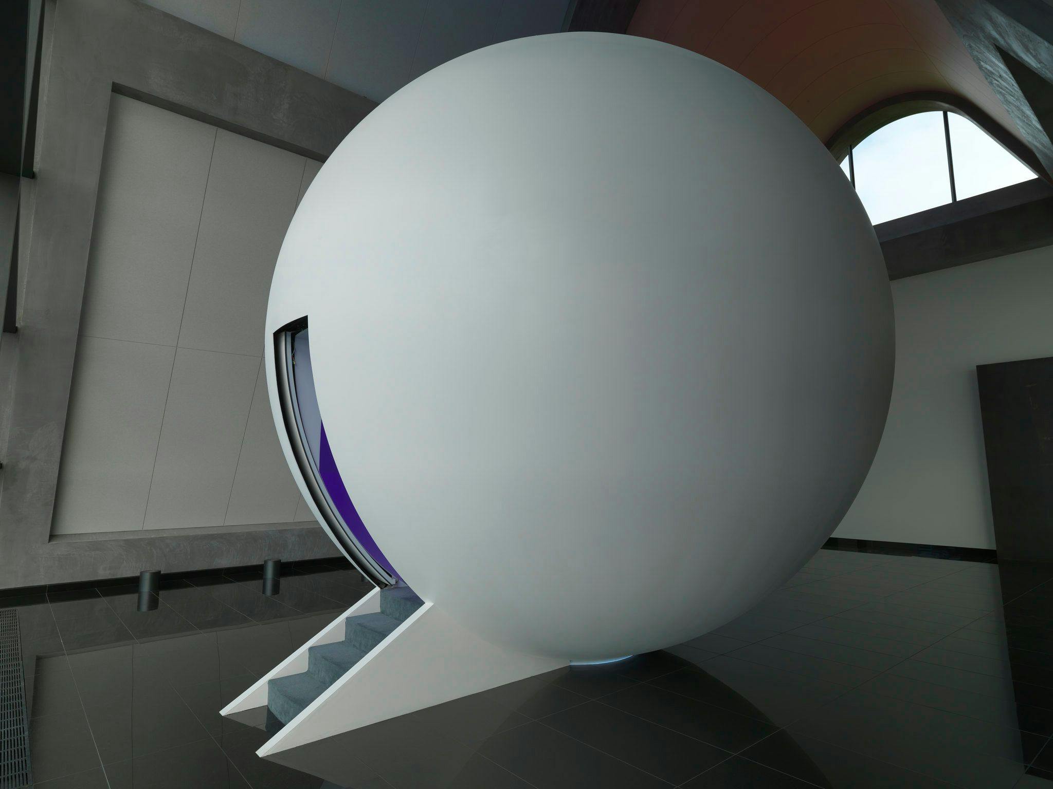 A large white sphere sits in the middle of our restaurant 'Faro'. On the left side of the sphere, a small staircase leads up to a doorway that allows entry into the dome.