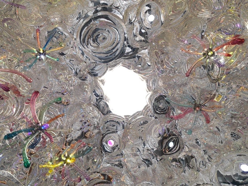 A swirling silver ceiling with coloured blown glass objects.
