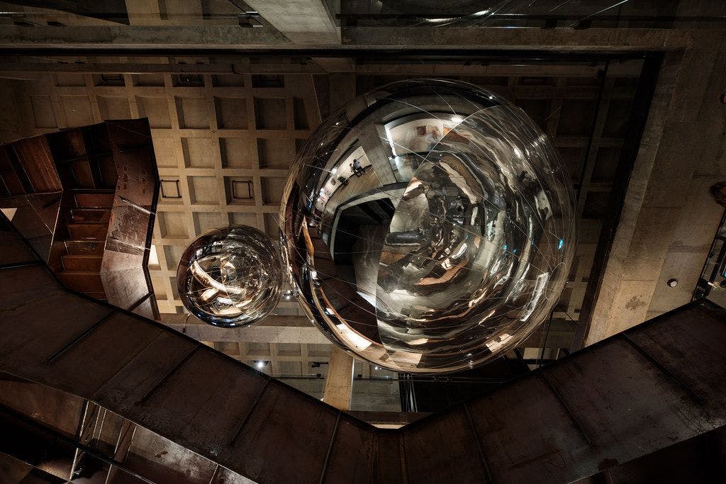 Two reflective circular spheres suspended from a ceiling.