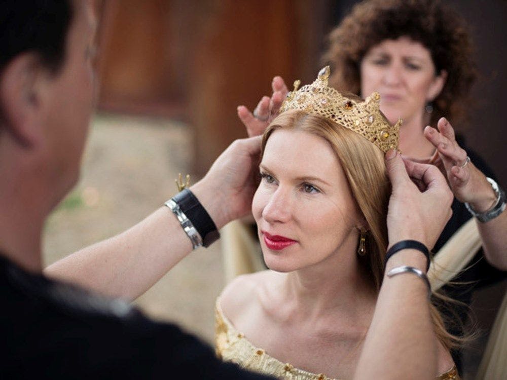 Kirsha having a golden crown placed upon her head with the help of two other people.