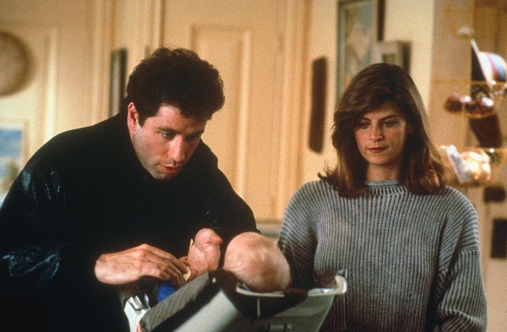 Still from the movie "Look who's talking" Kirsty Alley and John Travolta hover over a baby.