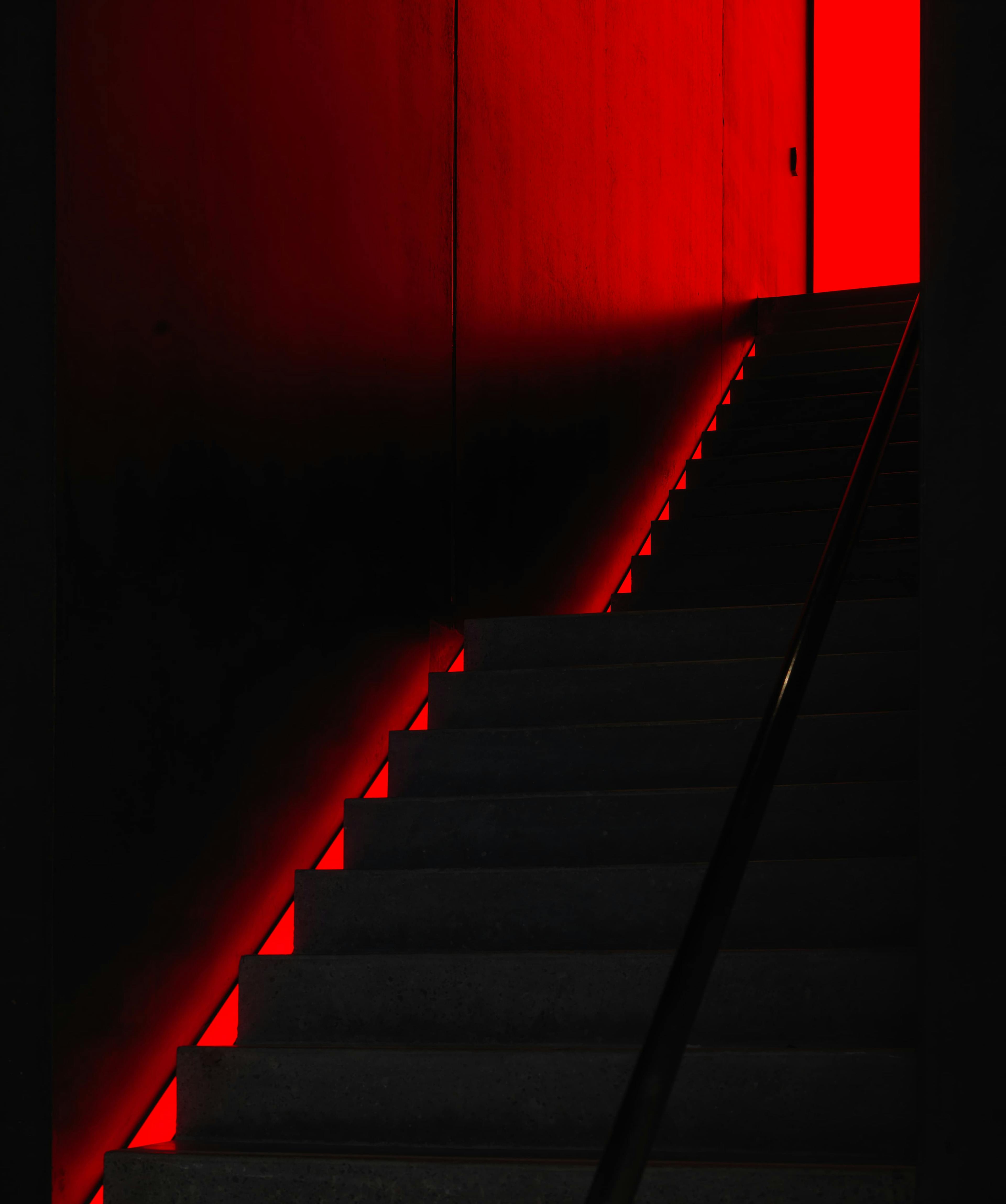 Looking up at an ominous, dark and dimly red lit stair case
