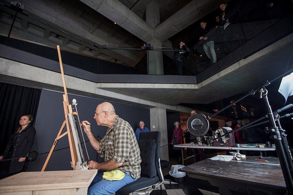 An artist painting on an easel inside the Museum.