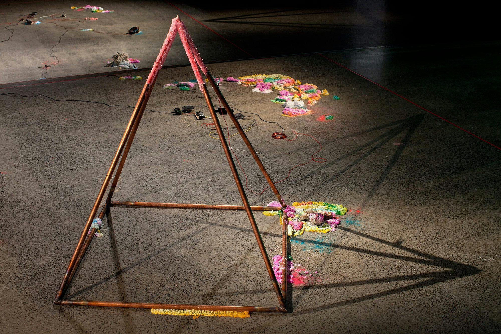 A pyramid casting shadows with brightly covered elements on and around