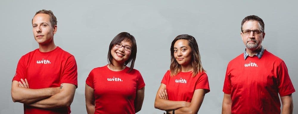 Four people in a uniform of a red t-shirt with the text "with."