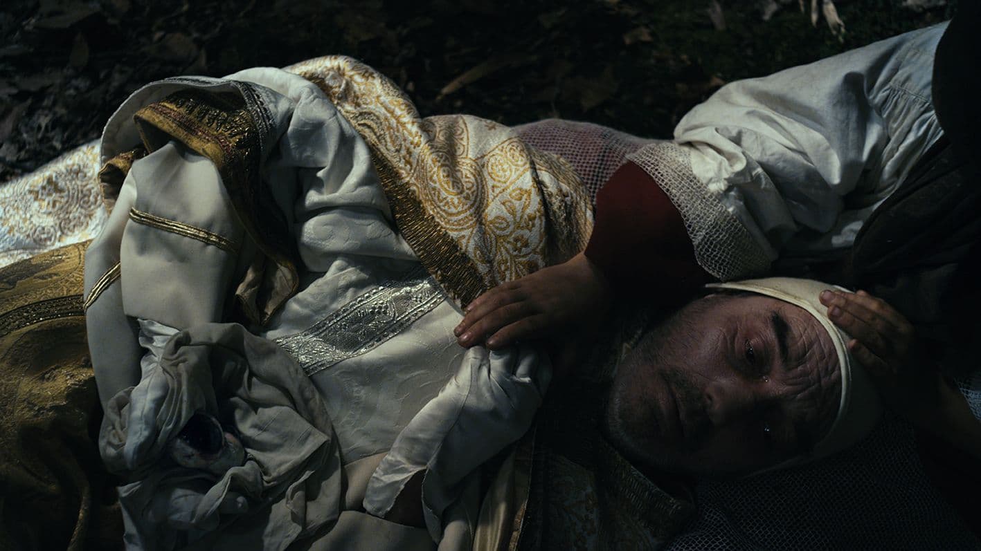 Image of a man in embroidered robes being comforted