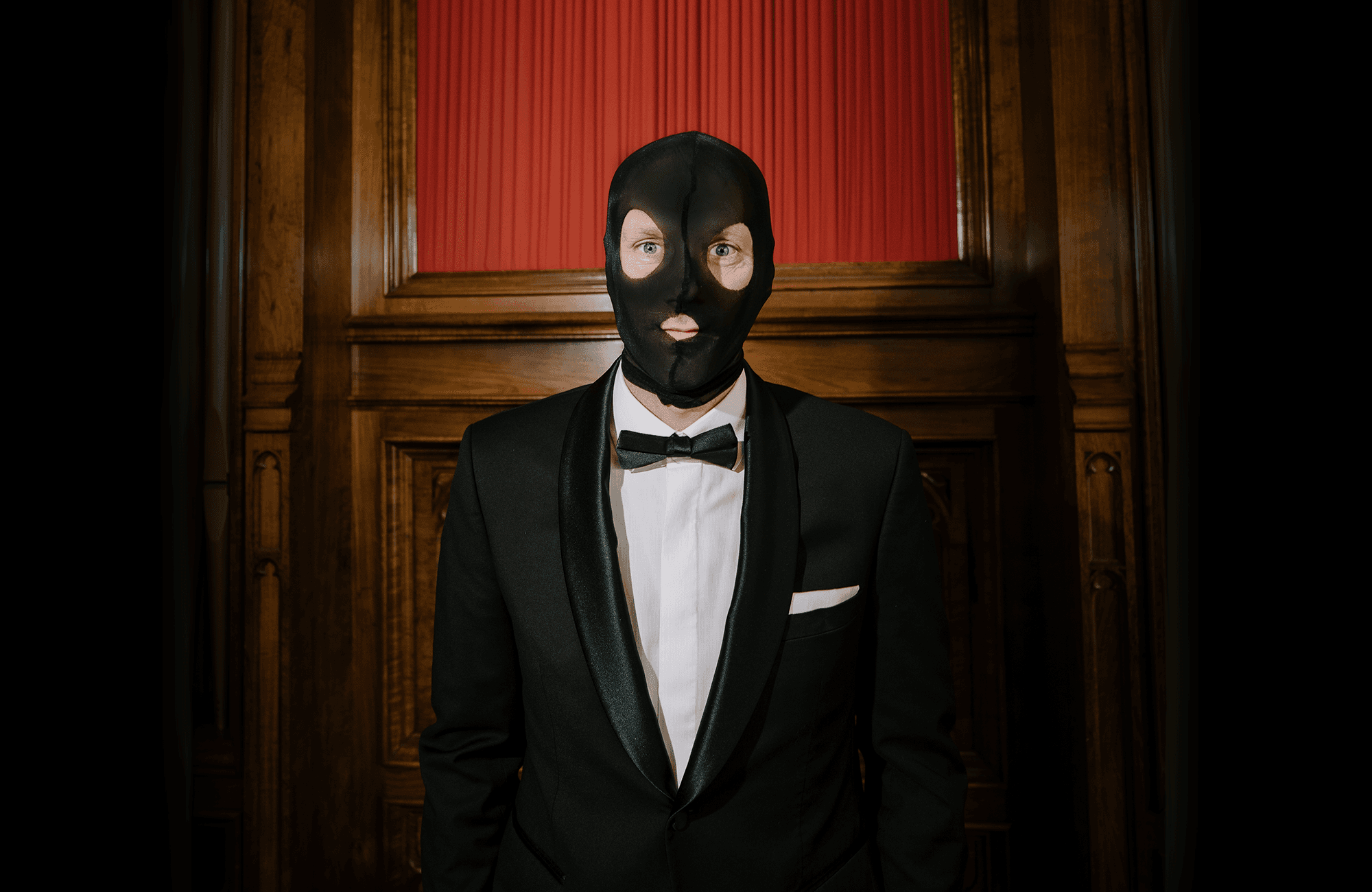A person wearing a black tuxedo and a black balaclava