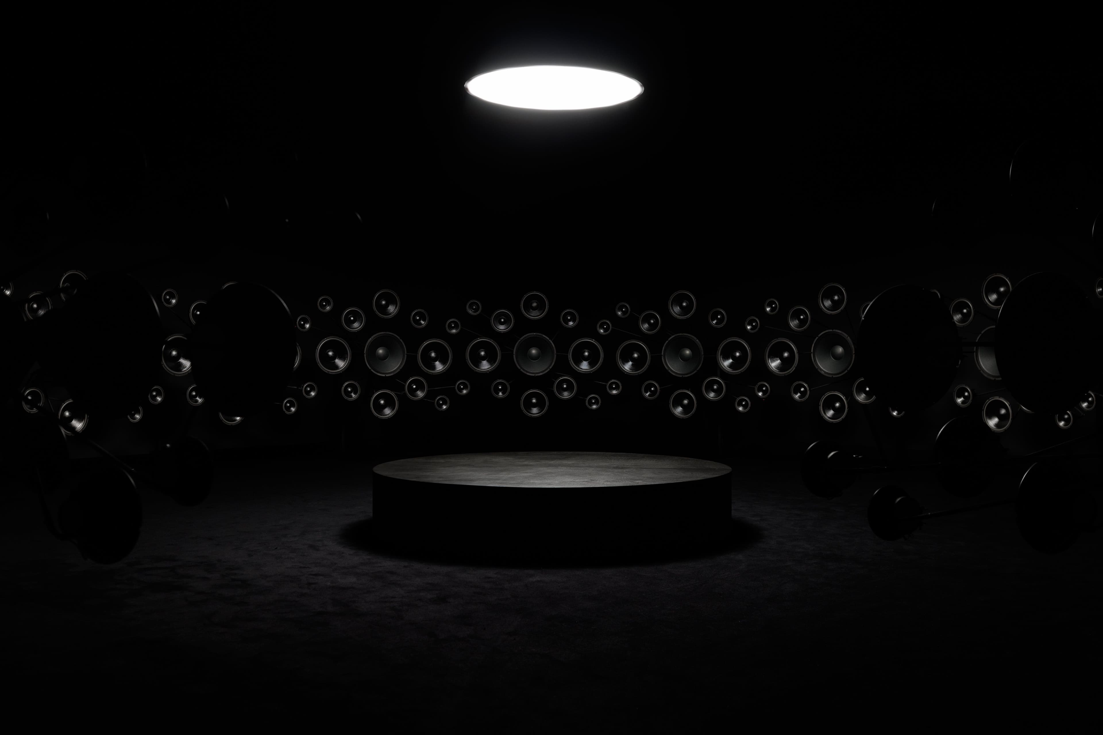 A dark circular room with speakers lining the walls.